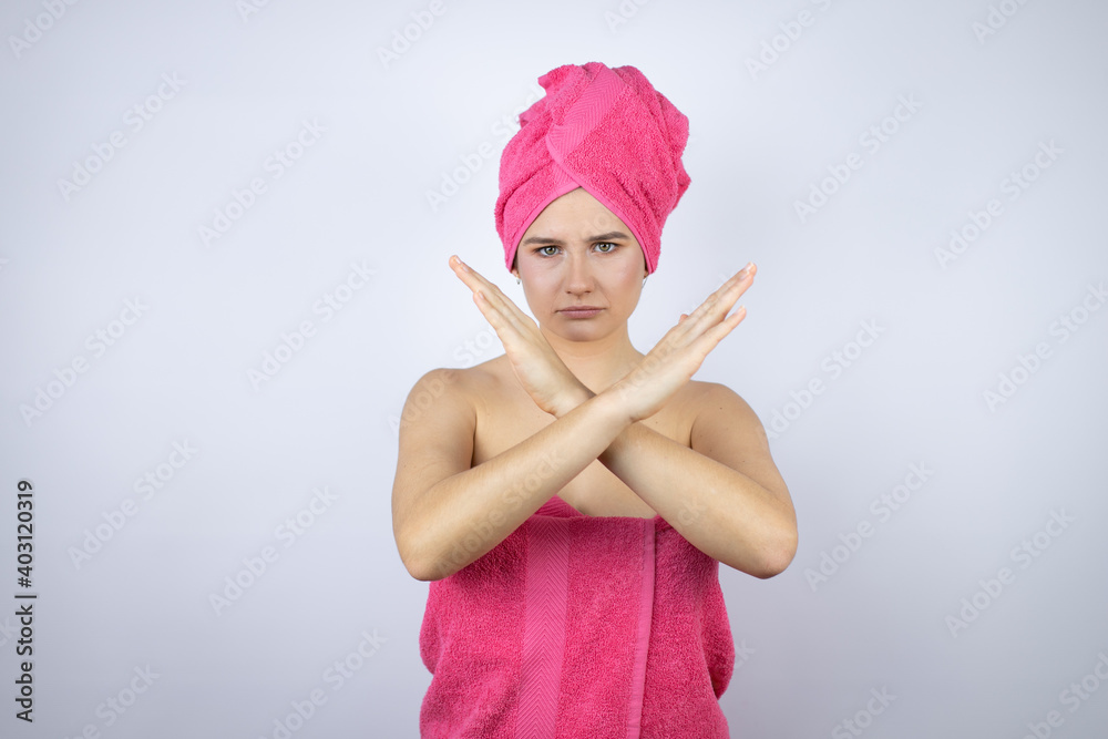 Young beautiful woman wearing shower towel after bath standing over isolated white background Rejection expression crossing arms doing negative sign, angry face Young beautiful woman wearing shower towel after bath standing over isolated white background Rejection expression crossing arms doing negative sign, angry face