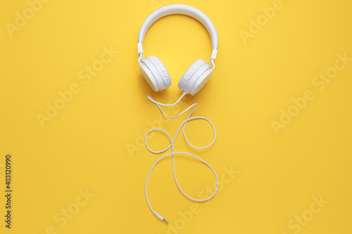 Modern white headphone on yellow background. Music concept.