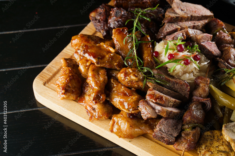 Pork kebab. Barbecue tasty meat ot the black plate. Potato, meat, and sausages. Pork kebab. Barbecue tasty meat ot the black plate. Potato, meat, and sausages.