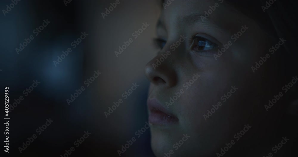 Cinematic macro shot of curious happy little girl while watching television screen in the dark. Concept of technology, new generation, family, connection, vision of the future of children with web. Cinematic macro shot of curious happy little girl while watching television screen in the dark. Concept of technology, new generation, family, connection, vision of the future of children with web.