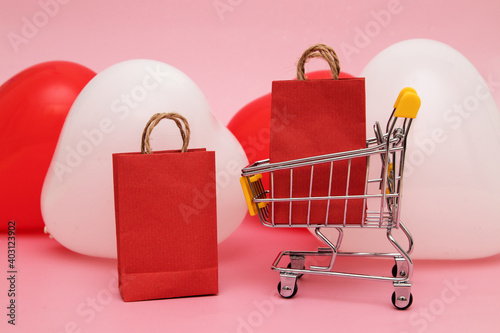 Supermarket trolley with purchases on the background of heart-shaped balloons - sale for valentine's day concept