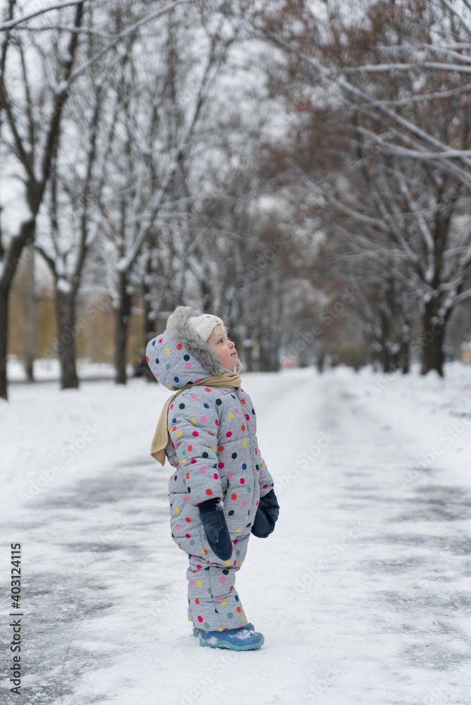 Little girl walks in winter park. Vertical frame