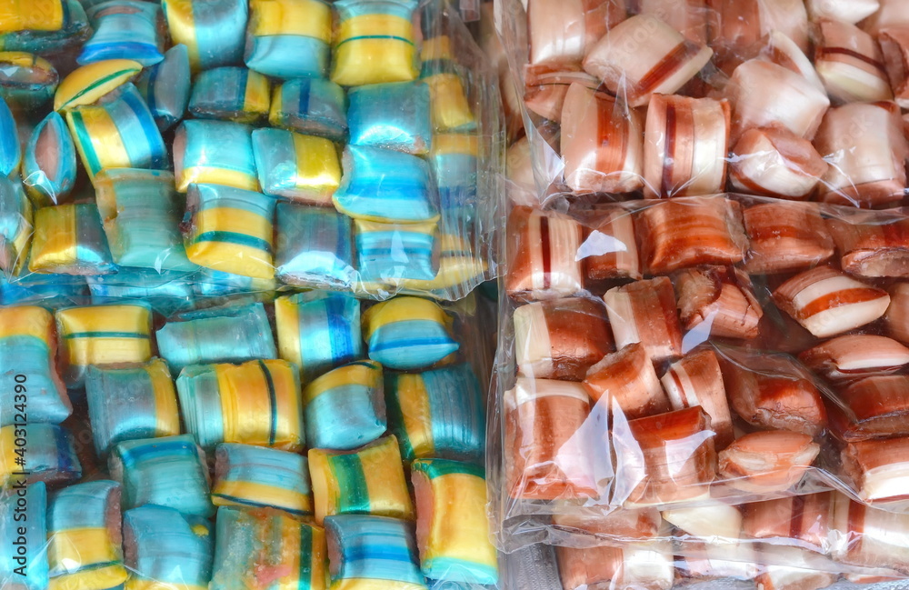 Multicolored candies in an transparent plastic wrap as a background.