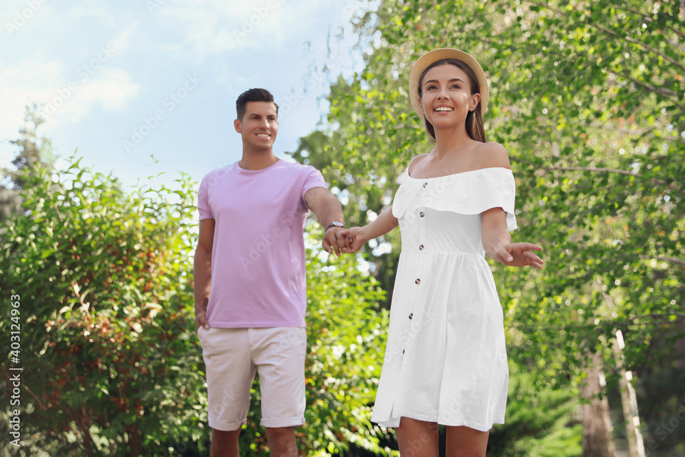 Lovely couple walking together in park on sunny day Lovely couple walking together in park on sunny day