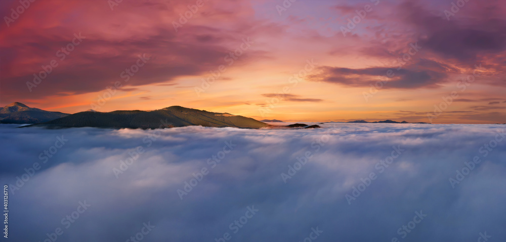Drmamtic sunrise sky above clouds and fog high in the mountains.