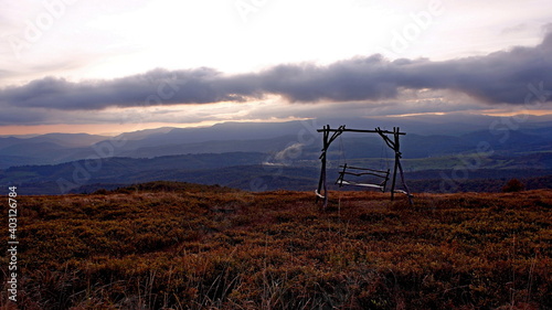 swing somewhere high in the mountains on a background of clouds and sunset in the autumn October evening