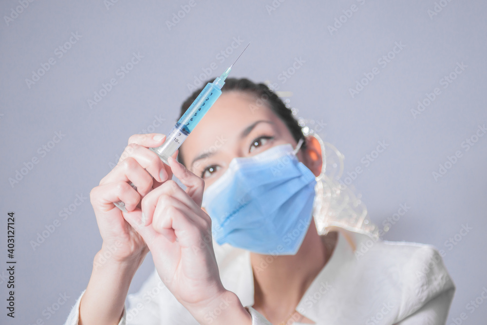 Médico mujer, preparando la vacuna para la cura del COVID 19, SARS-CoV-2, cura definitiva, vacuna en tonos azules y colores neutros, mujer preparando la inyección en una jeringa para curar el SARS-Co Médico mujer, preparando la vacuna para la cura del COVID 19, SARS-CoV-2, cura definitiva, vacuna en tonos azules y colores neutros, mujer preparando la inyección en una jeringa para curar el SARS-Co