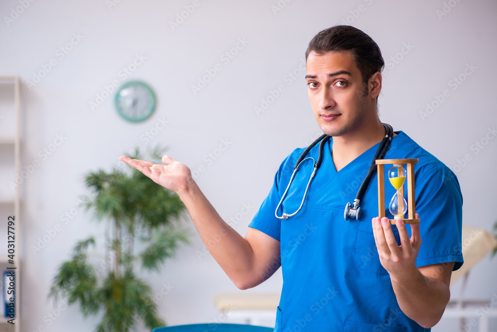 Young male doctor in time management concept Young male doctor in time management concept