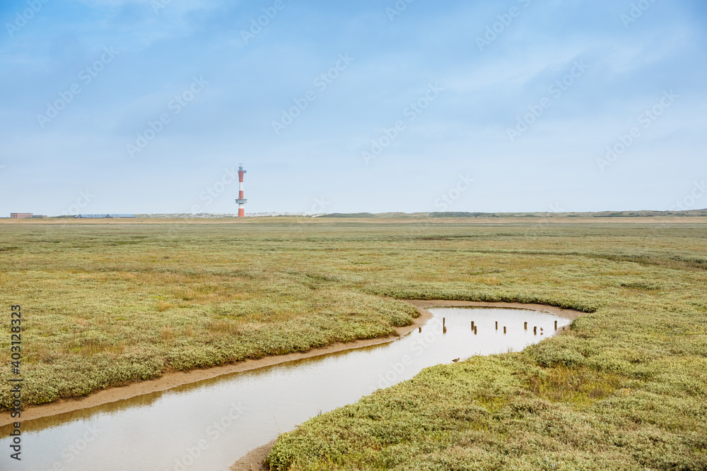 Small white and red lighthouse on a North Sea island. Landscape photo from East Frisia