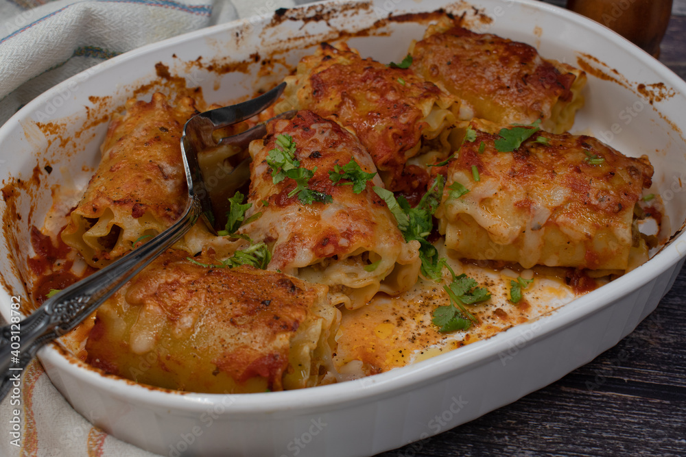 Vegetarian lasagna rolls filled with seitan in white dish on wooden .table, close up Vegetarian lasagna rolls filled with seitan in white dish on wooden .table, close up