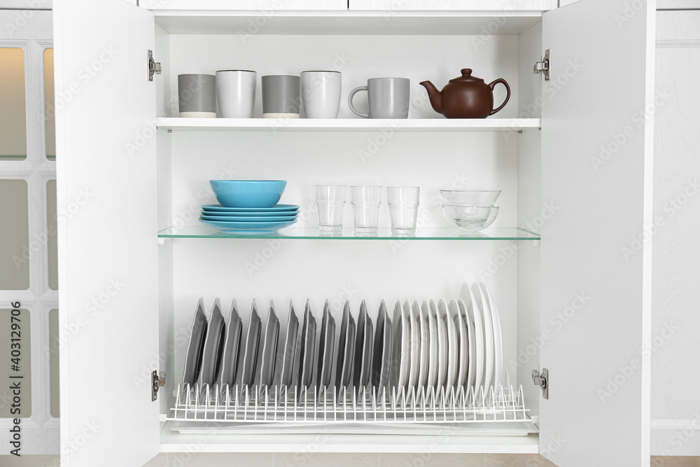 Open cabinet with different clean dishware in kitchen Open cabinet with different clean dishware in kitchen
