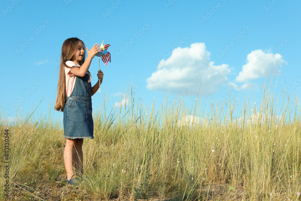 Cute little girl with pinwheel outdoors, space for text. Child spending time in nature