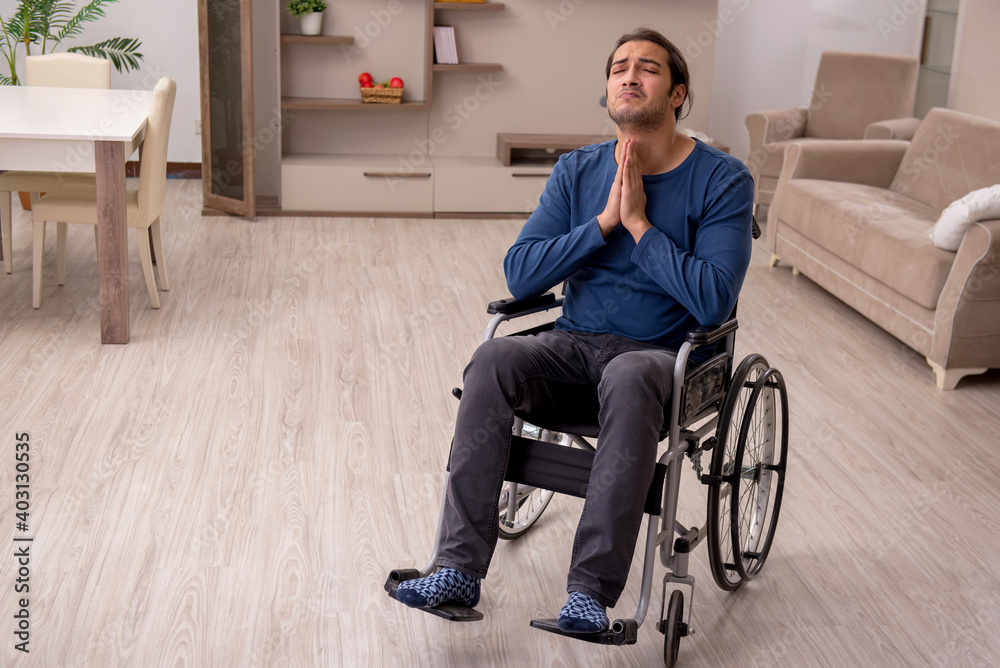Young man in wheel-chair suffering at home Young man in wheel-chair suffering at home
