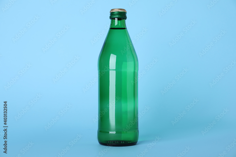 Glass bottle with water on light blue background Glass bottle with water on light blue background