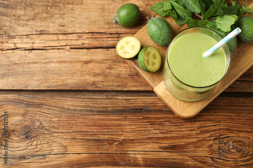Fresh feijoa smoothie and ingredients on wooden table, flat lay. Space for text