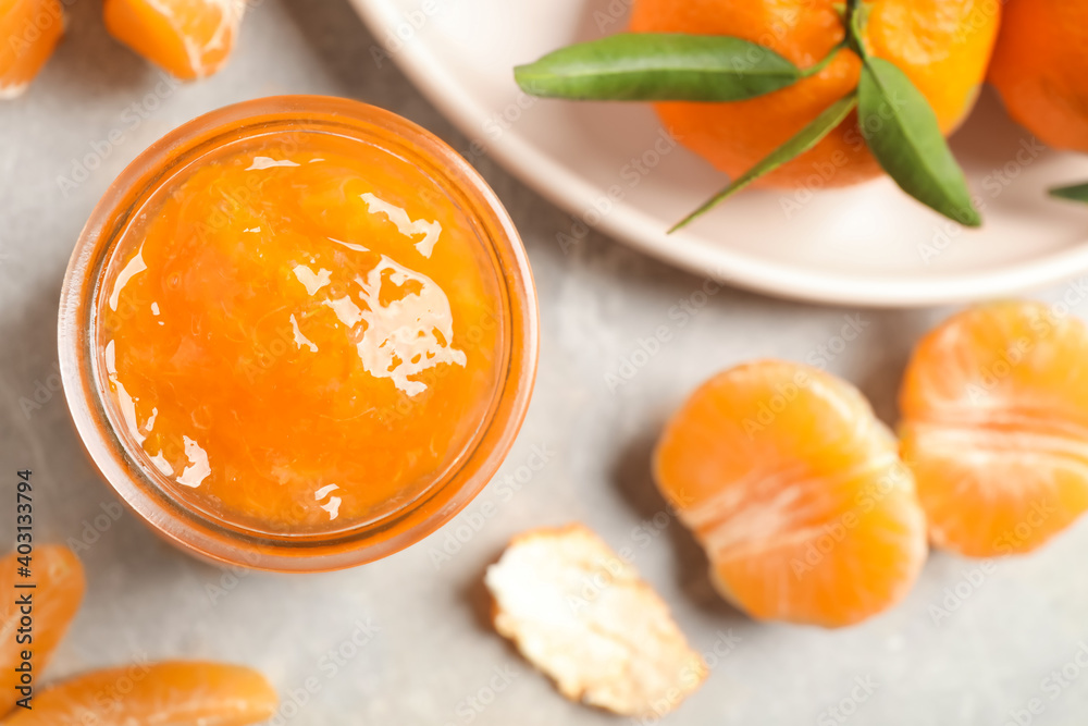 Tasty jam and fresh tangerines on light grey table, flat lay. Space for text Tasty jam and fresh tangerines on light grey table, flat lay. Space for text