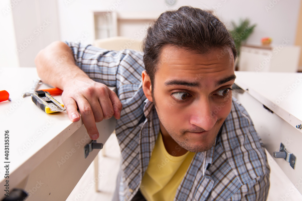 Young male carpenter repairing furniture at home Young male carpenter repairing furniture at home