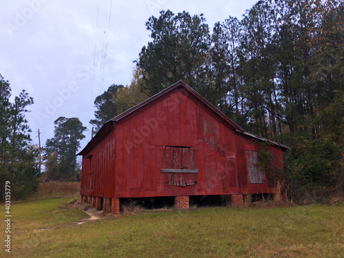 A red barn style building boarded up and abandoned
