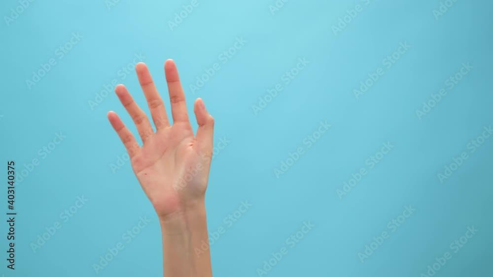 Close up of woman hand showing waving bye on the blue background.