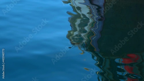 Reflections of a fishing boat in the moving ocean. photo