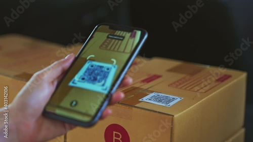 Startup small business, hand using smartphone with scan QR code on cardboard box delivery for products to send to customers.