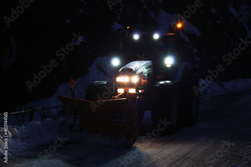 snowplow passes through the snowy mountain streets in the evening to clean up the road traffic