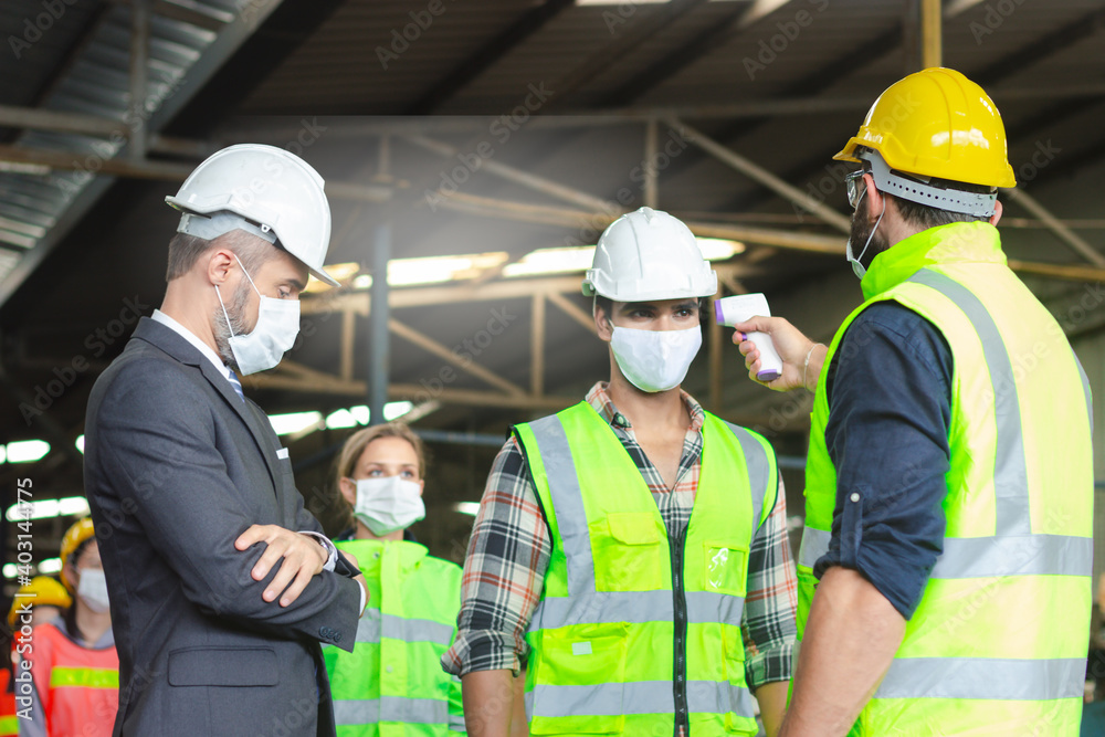 Foreman hold digital thermometer, measure temperature for screen workers with face mask, prevent against infection of Covid-19 outbreak, industrial engineers in line at manufacturing industry factory Foreman hold digital thermometer, measure temperature for screen workers with face mask, prevent against infection of Covid-19 outbreak, industrial engineers in line at manufacturing industry factory