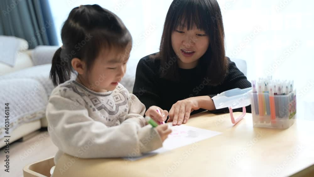 mother and daughter are drawing on a table mother and daughter are drawing on a table