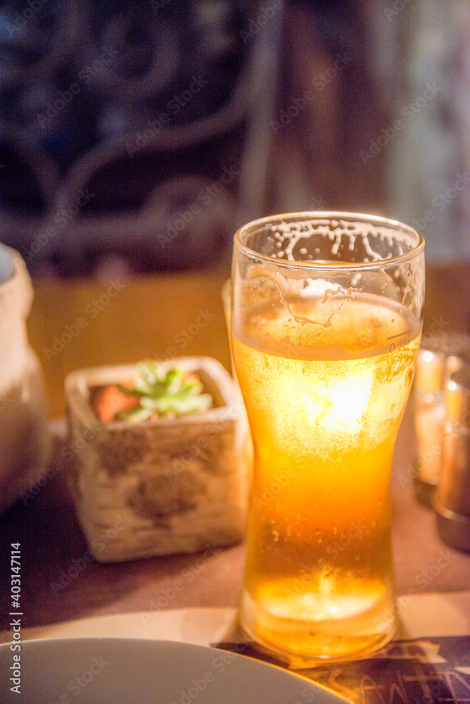 Candlelight shiining through a glass of beer on a restaurant table at night surrounded by condiment bottles ,Kotor,Montenegro. Candlelight shiining through a glass of beer on a restaurant table at night surrounded by condiment bottles ,Kotor,Montenegro.