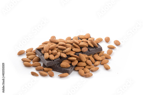 almonds piled onto a slab of raw chocolate as ingredients for a chocolate bar isolated on white



