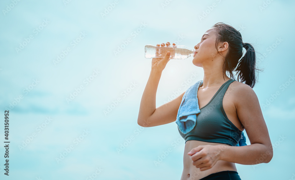 Asian female jogger drinking fresh water after training.Young athletic woman exercising on the rocks at beach.Fitness ,workout, gym exercise ,lifestyle and healthy concept. Asian female jogger drinking fresh water after training.Young athletic woman exercising on the rocks at beach.Fitness ,workout, gym exercise ,lifestyle and healthy concept.