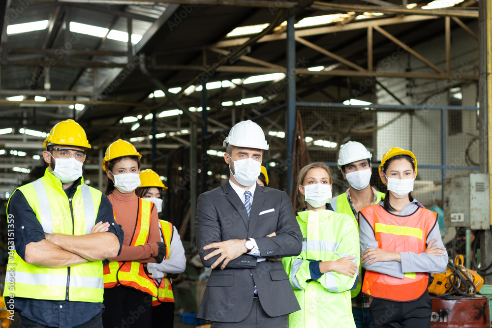 Large group of confident industrial engineer worker and foreman boss with face mask wearing safety equipment standing with arms crossed at manufacturing plant factory Large group of confident industrial engineer worker and foreman boss with face mask wearing safety equipment standing with arms crossed at manufacturing plant factory