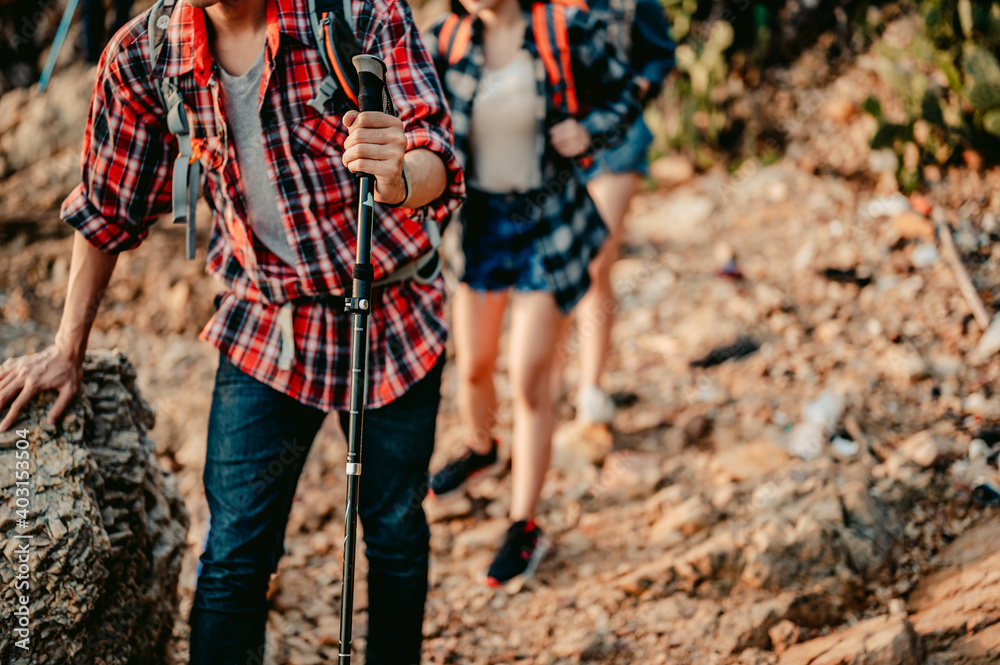 A group of hikers travel through the rocks using trekking poles to support them.Travel and adventure concept. A group of hikers travel through the rocks using trekking poles to support them.Travel and adventure concept.