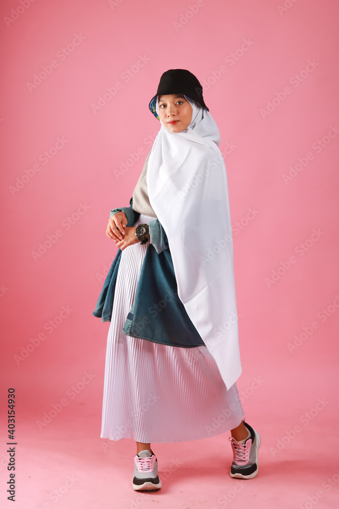 Fashion portrait of young beautiful asian muslim woman with wearing hijab isolated on pink background.