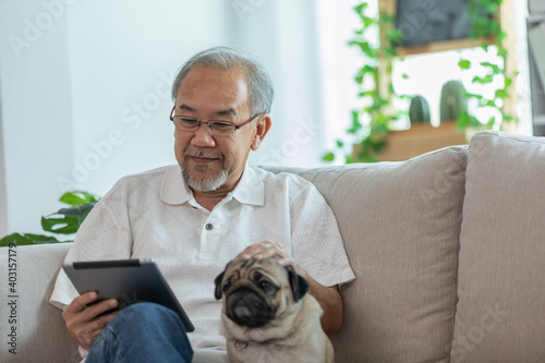 Photography Happiness elderly asian man sitting on sofa and using computer tablet and smile