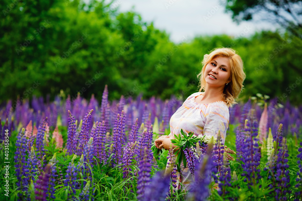 Beautiful young blonde on a green field among purple lupine wildflowers. Wildlife is a beautiful girl. Beautiful young blonde on a green field among purple lupine wildflowers. Wildlife is a beautiful girl.