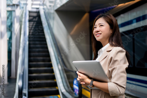 Asian business women going to work in the morning on the subway She was smiling and was holding a laptop.