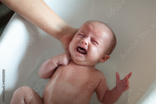 Canvas Print Newborn baby is being bathed by his mother