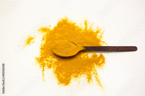 Turmeric powder in wooden spoon. White background.