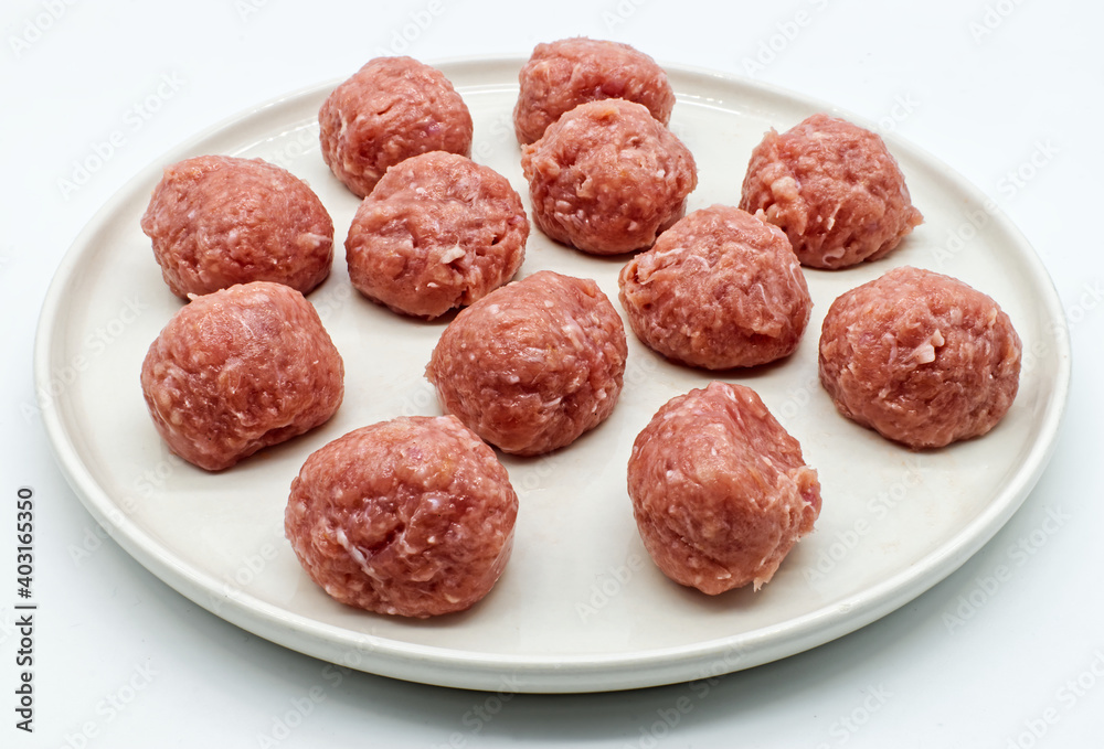 Raw meatballs with peas in a white dish isolated on white background. Raw meatballs with peas in a white dish isolated on white background.