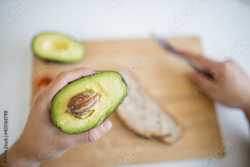 Male hand holding sliced avocado above a cutting board