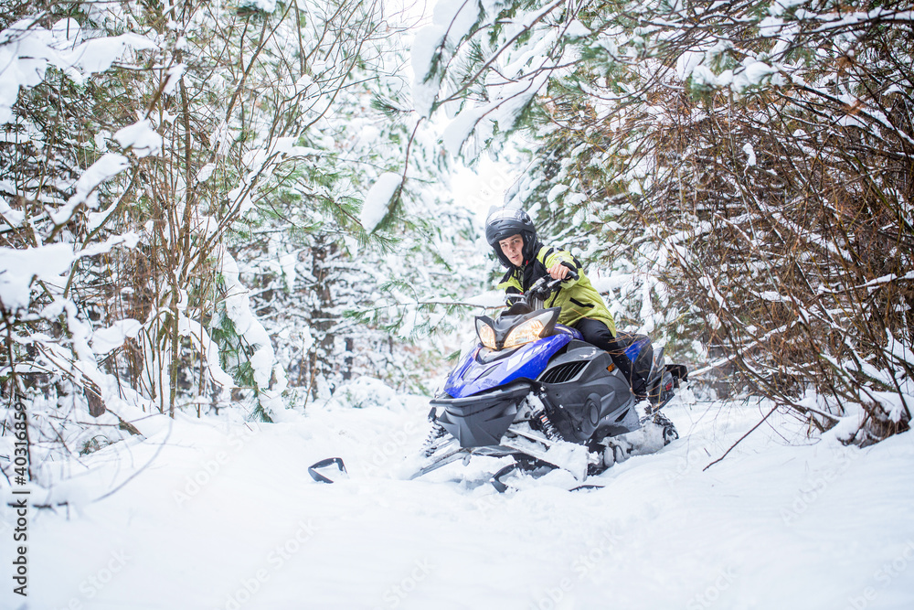 Man on snowmobile in winter mountain. Snowmobile driving. Man driving snowmobile in snowy forest