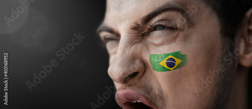 A screaming man with the image of the Brazil national flag on his face