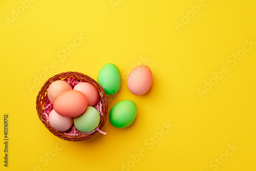 Decorative nest with colorful Easter eggs on yellow background
