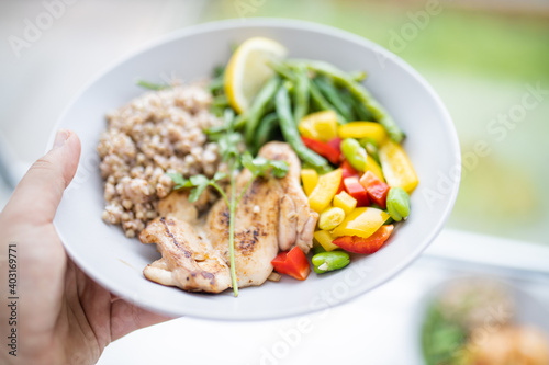 Hand holding a chicken and buckwheat dish with green beans