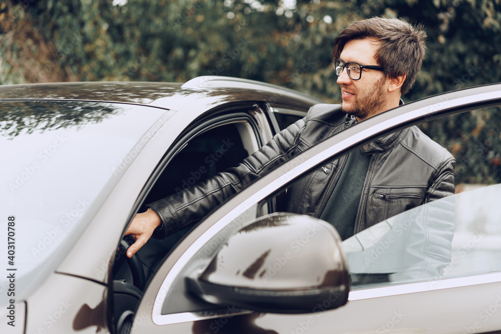 Stylish man in glasses sits in a car