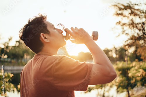 handsome man drinking water on a sunny day after running. Sport, fitness workout concept.