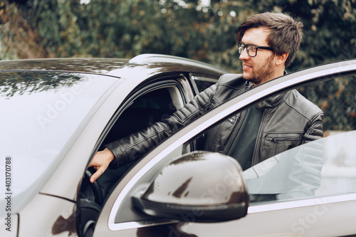Stylish man in glasses sits in a car