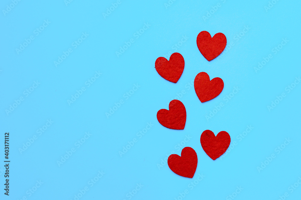 Red paper hearts on blue background top view