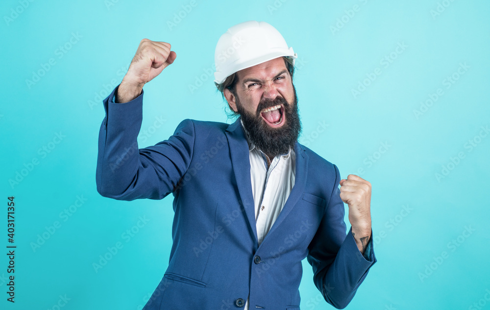successful man with beard and moustache in helmet look as businessman on construction site, celebrate success